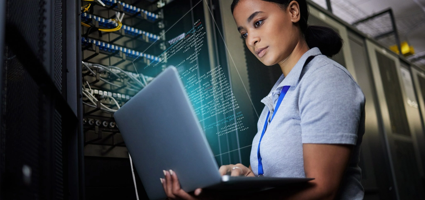 an IT professional working on a laptop, with abstract coding/’hacking’-style imagery overlaid.