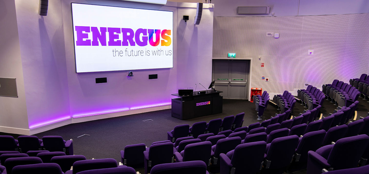 Modern conference auditorium at Energus event venue featuring a large presentation screen, tiered seating, and advanced audiovisual technology for corporate events, conferences, training sessions, and business presentations.