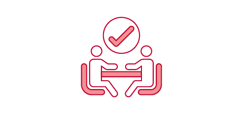 Two people sitting at a table, with a checkmark above them.