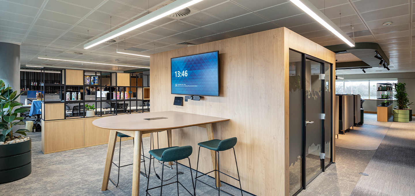 Waiting area with green walls, chairs, and a COVID‑19 vaccination information poster displayed on a screen.