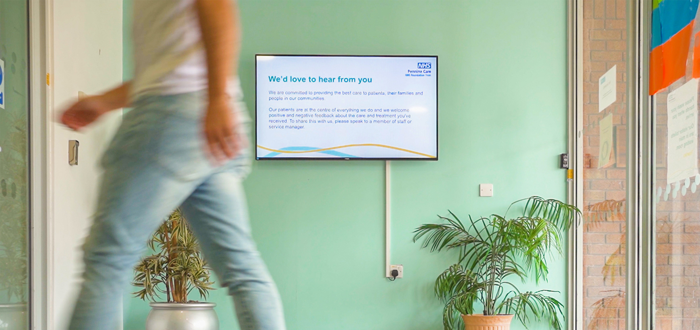 Digital information screen in a healthcare facility showing patient feedback message in a reception area.