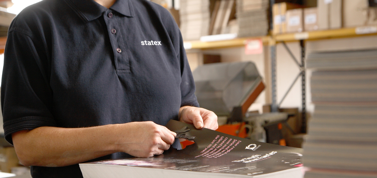 A professional operator handling high‑quality printed materials inside a busy production facility, showcasing precision, craftsmanship, and reliable print finishing.