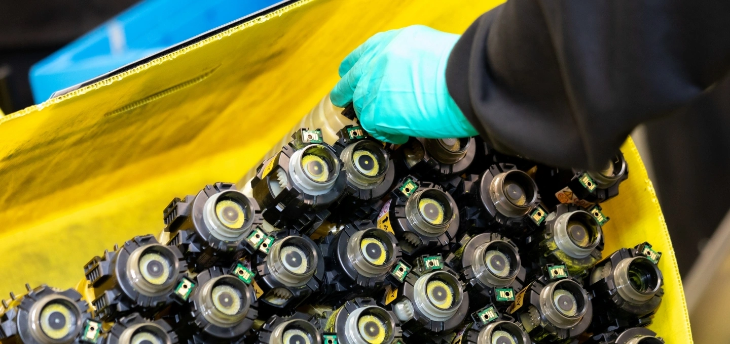 A hand reaching into a container of toner bottles.